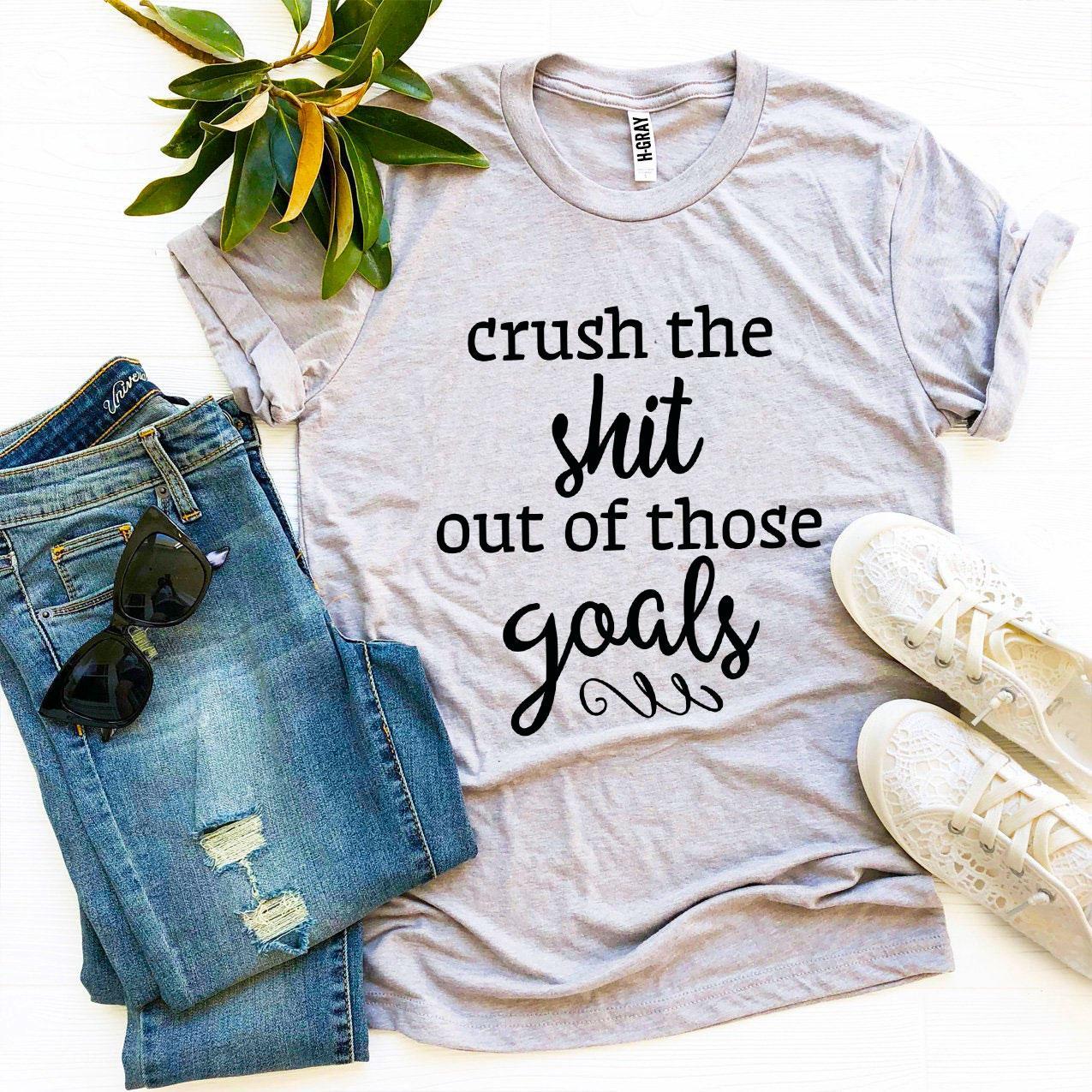 A stylish black t-shirt with the phrase 'Crush The Shit Out Of Those Goals' printed in bold white letters, showcasing its premium quality and soft fabric.