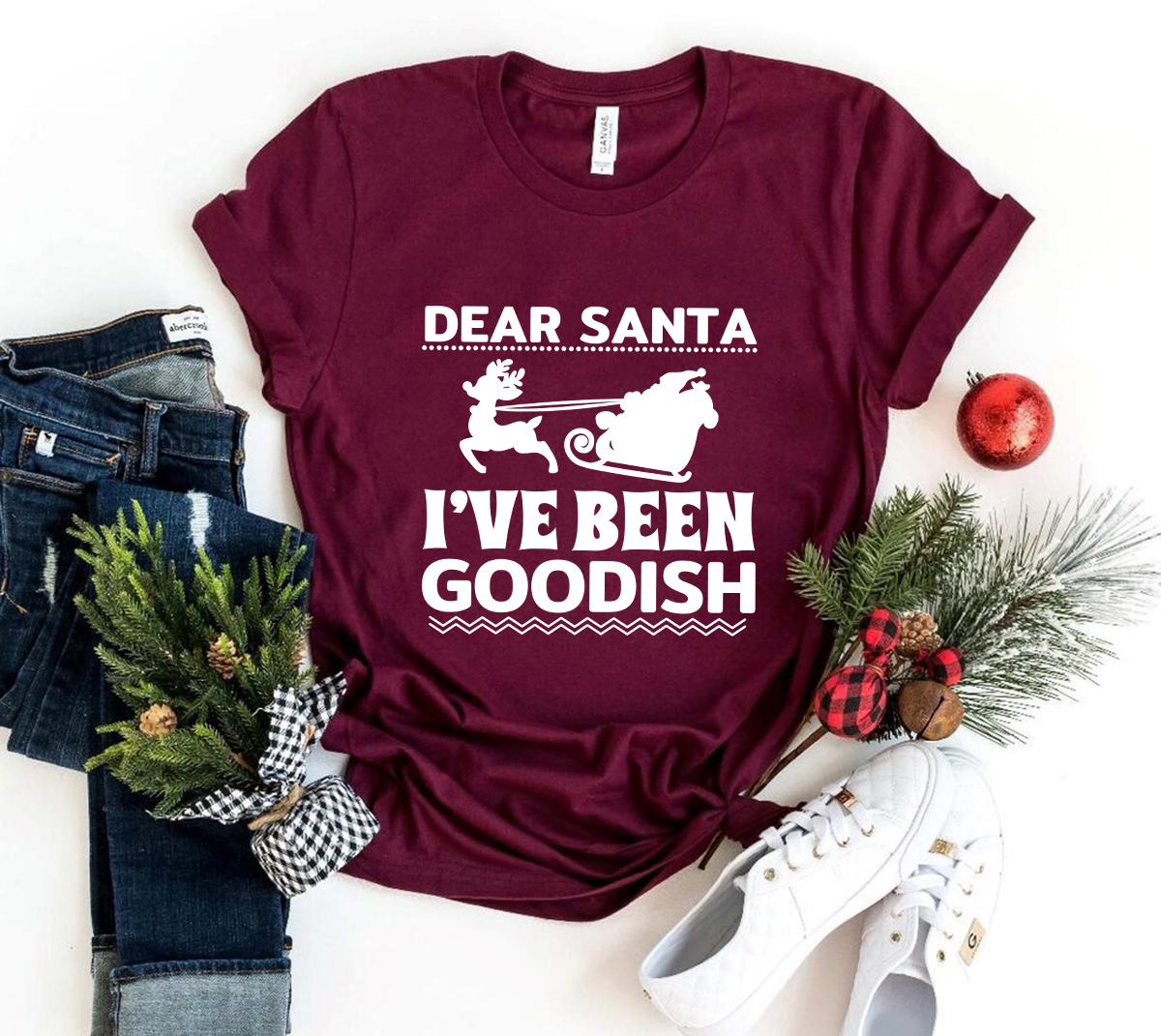 A unisex T-shirt featuring the phrase 'Dear Santa I've Been Goodish' in a playful font, made from soft ring spun cotton, available in various colors.