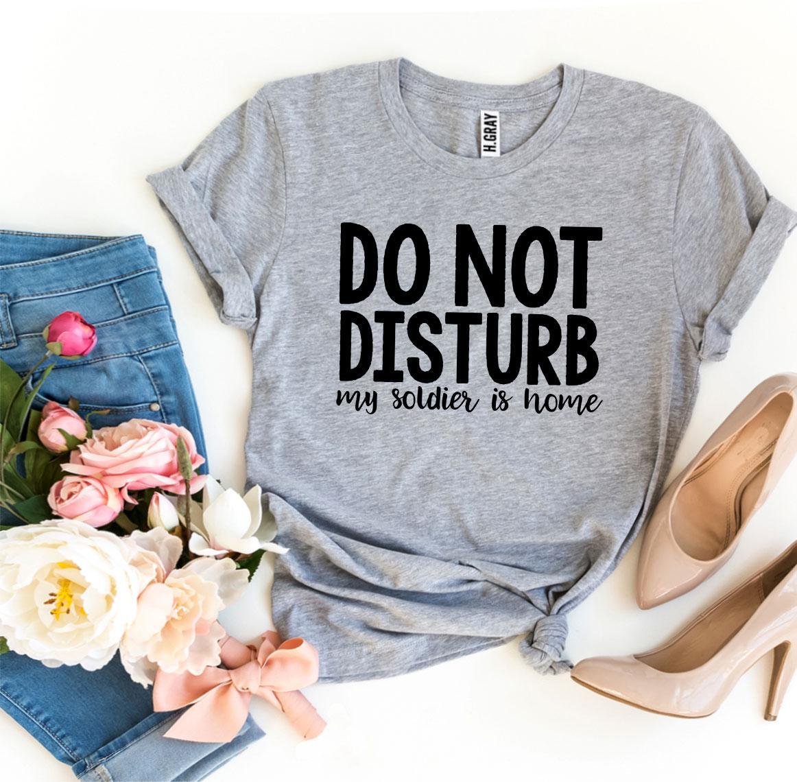 A black T-shirt with the text 'Do Not Disturb My Soldier Is Home' printed in bold letters, showcasing a comfortable and stylish design.