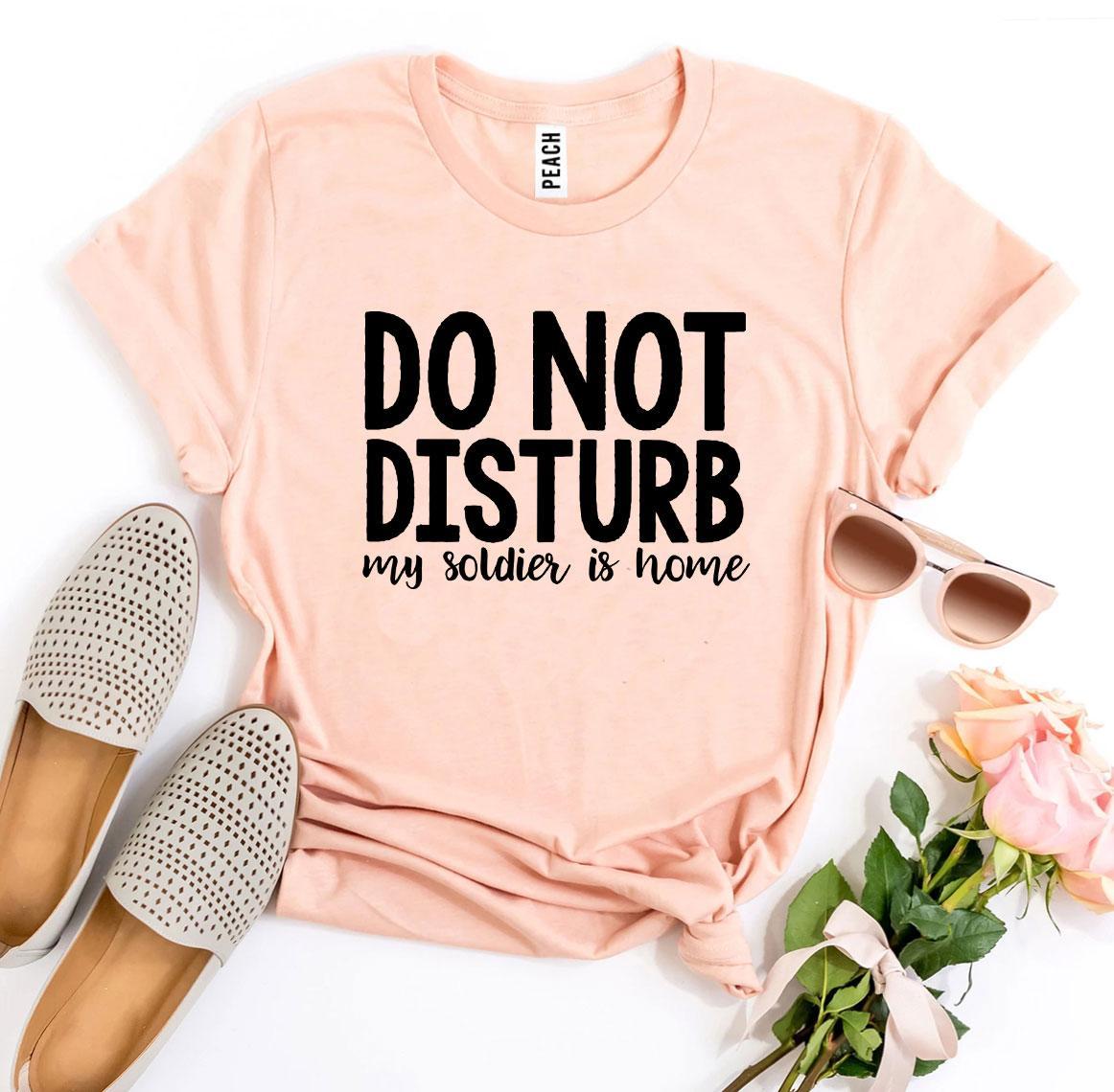 A black T-shirt with the text 'Do Not Disturb My Soldier Is Home' printed in bold letters, showcasing a comfortable and stylish design.