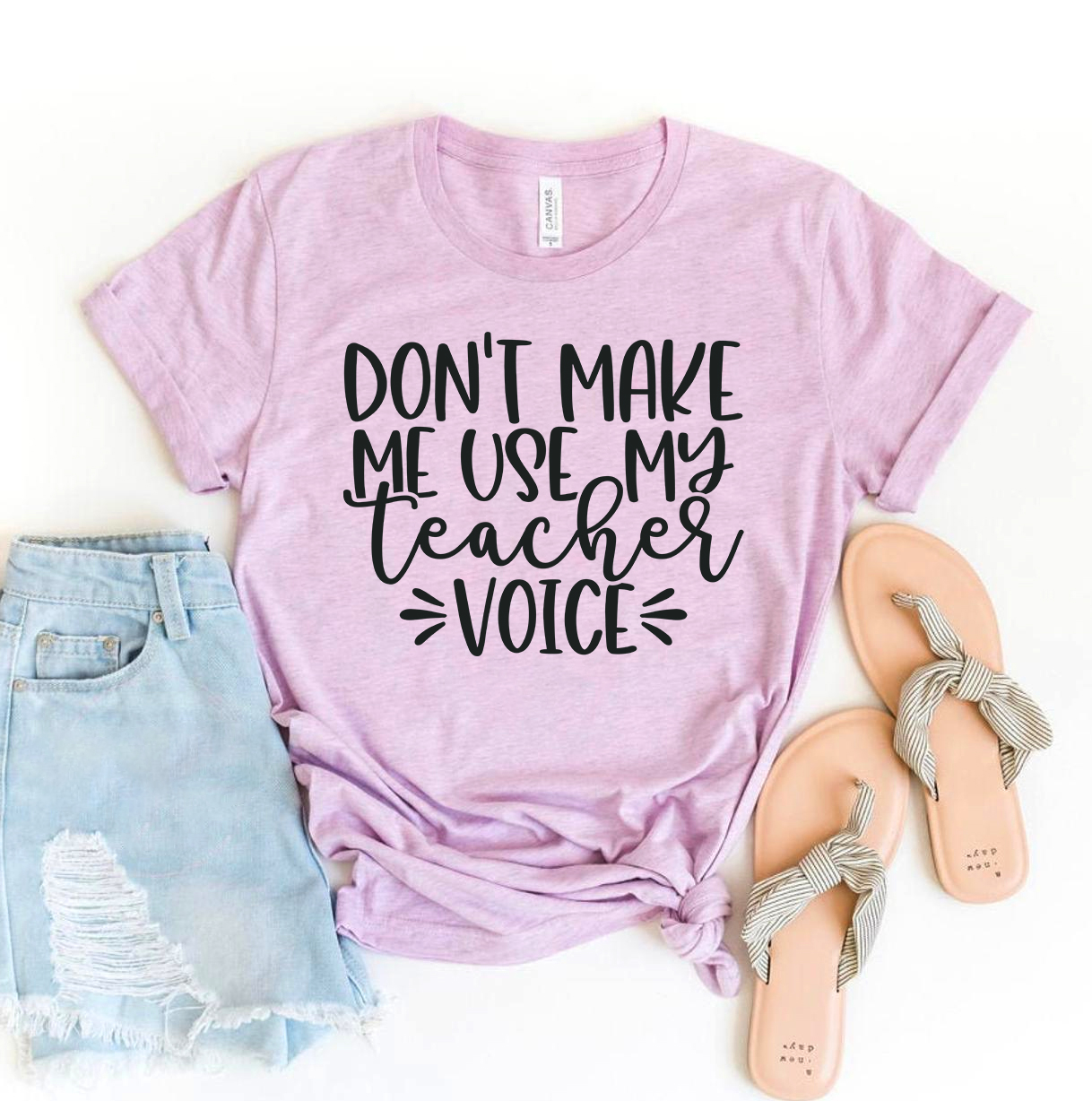 A stylish black t-shirt featuring the phrase 'Don't Make Me Use My Teacher Voice' in bold white letters, made from premium ring spun cotton.