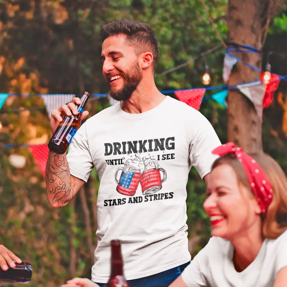 A stylish 4th of July tee featuring the phrase 'Drinking Until I See The Stars And Stripes' in a vibrant design, perfect for summer celebrations.