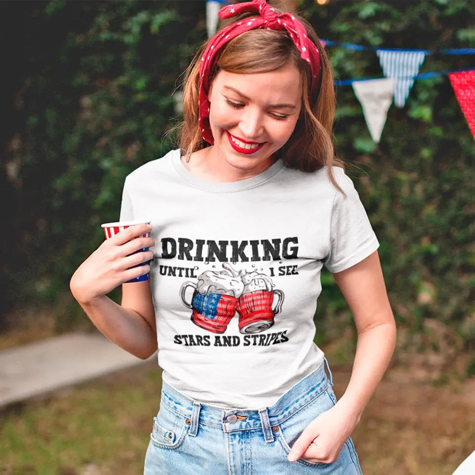 A stylish 4th of July tee featuring the phrase 'Drinking Until I See The Stars And Stripes' in a vibrant design, perfect for summer celebrations.