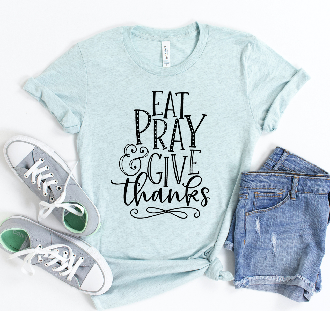 Eat Pray & Give Thanks T-shirt displayed on a hanger, showcasing its soft fabric and classic design.