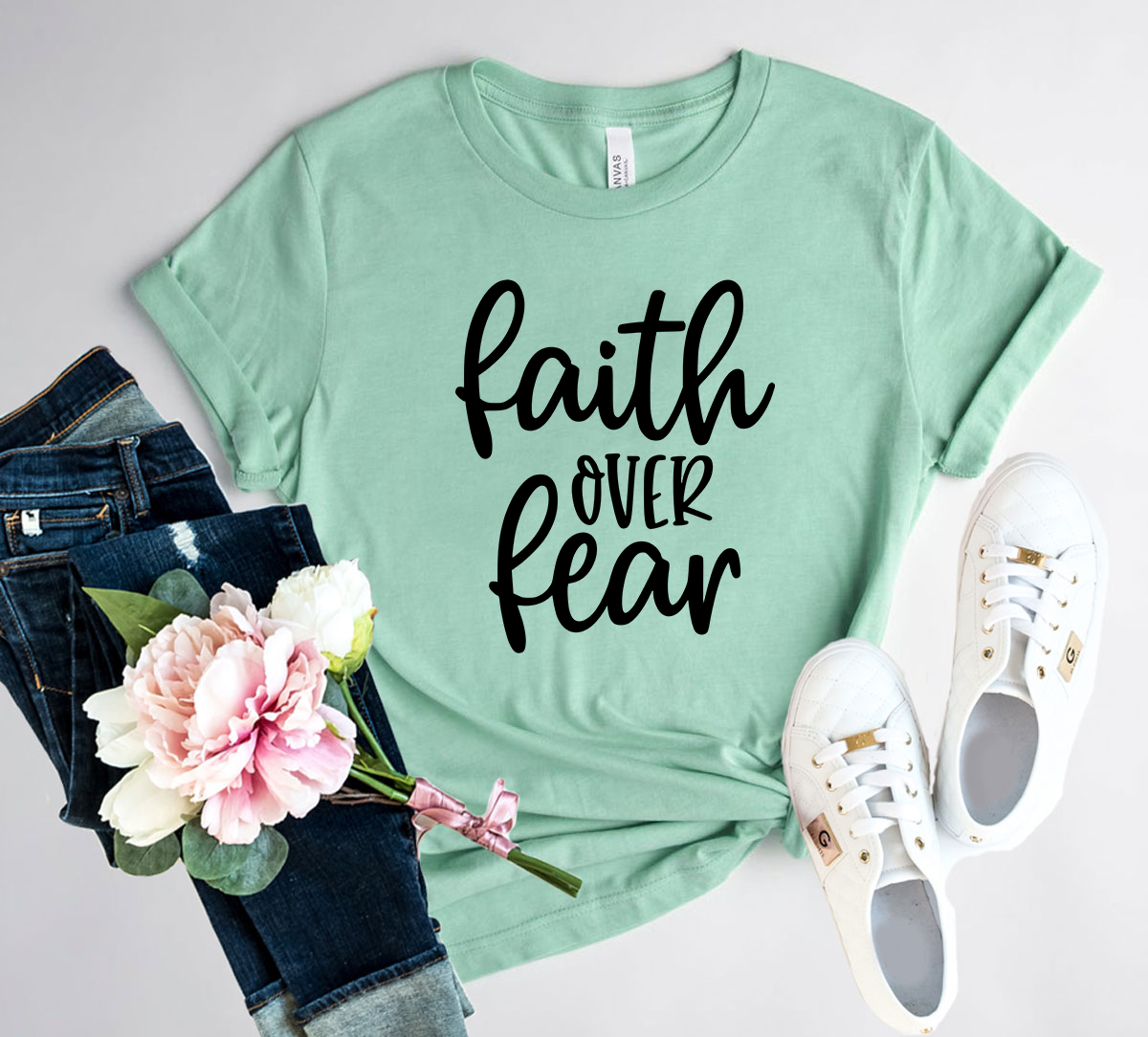 A unisex Faith Over Fear shirt made from soft ring spun cotton, featuring a bold print of the phrase 'Faith Over Fear' in vibrant colors.