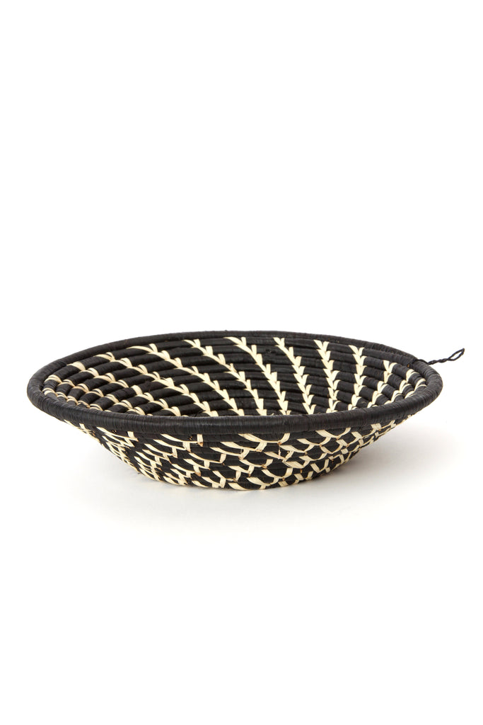 Handwoven African wall basket featuring cream swirls on black raffia, showcasing intricate craftsmanship by Ugandan artisans.