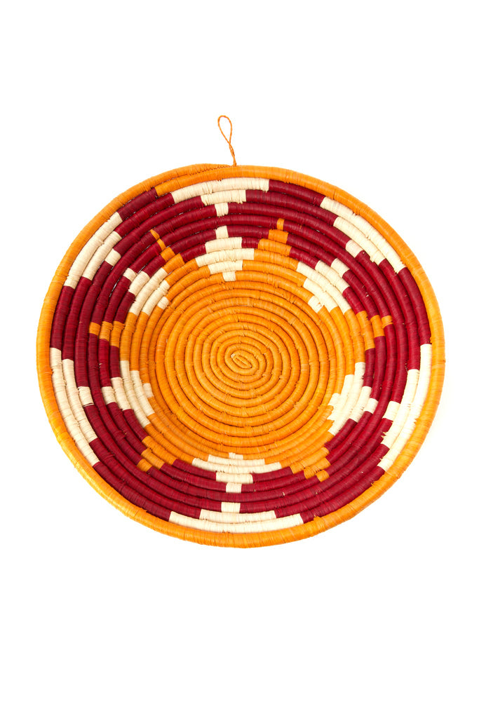 Handwoven sisal coiled African raffia basket in vibrant orange and burgundy, showcasing intricate craftsmanship and natural materials.