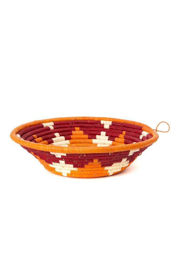 Handwoven sisal coiled African raffia basket in vibrant orange and burgundy, showcasing intricate craftsmanship and natural materials.