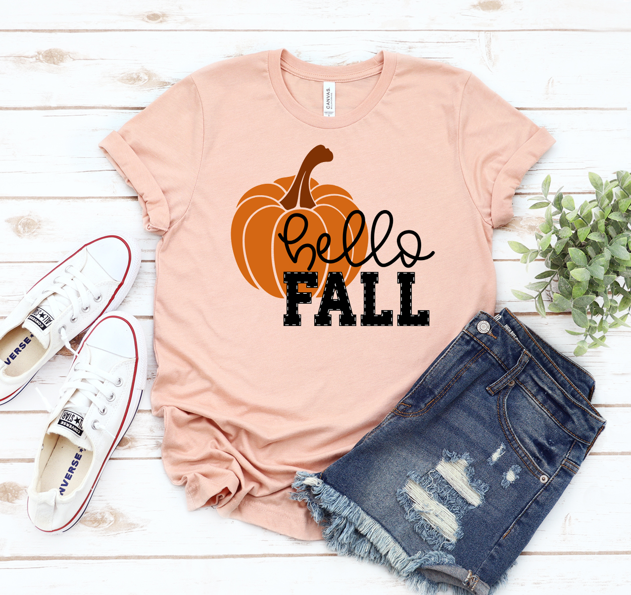 Hello Fall T-shirt displayed on a wooden background, showcasing its unisex design and soft fabric.