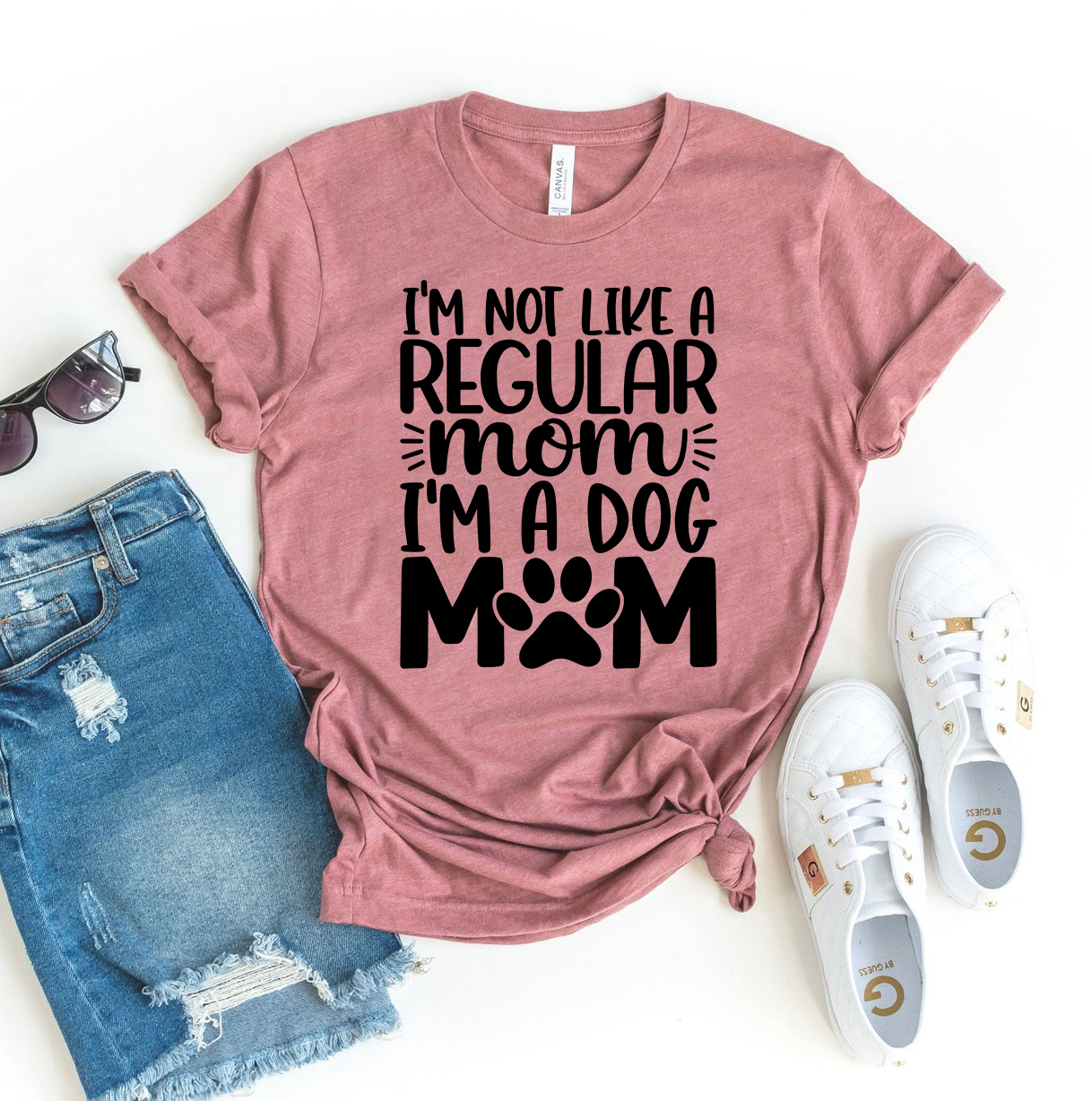 A stylish black T-shirt with the text 'I'm Not Like A Regular Mom I'm Dog Mom' printed in white, showcasing a fun design for dog lovers.