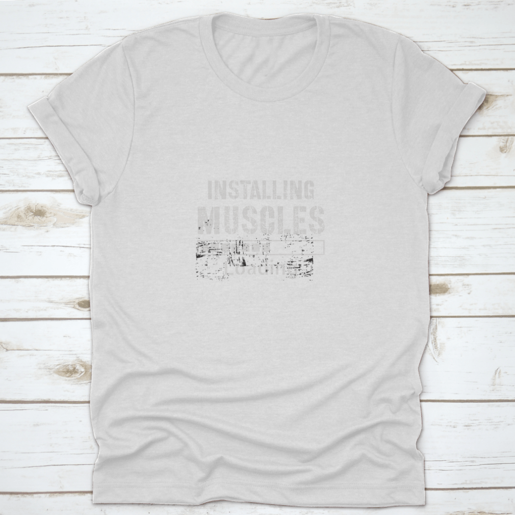 A vintage-inspired t-shirt featuring a grunge background with the phrase 'Installing Muscles', made from 100% cotton for comfort.