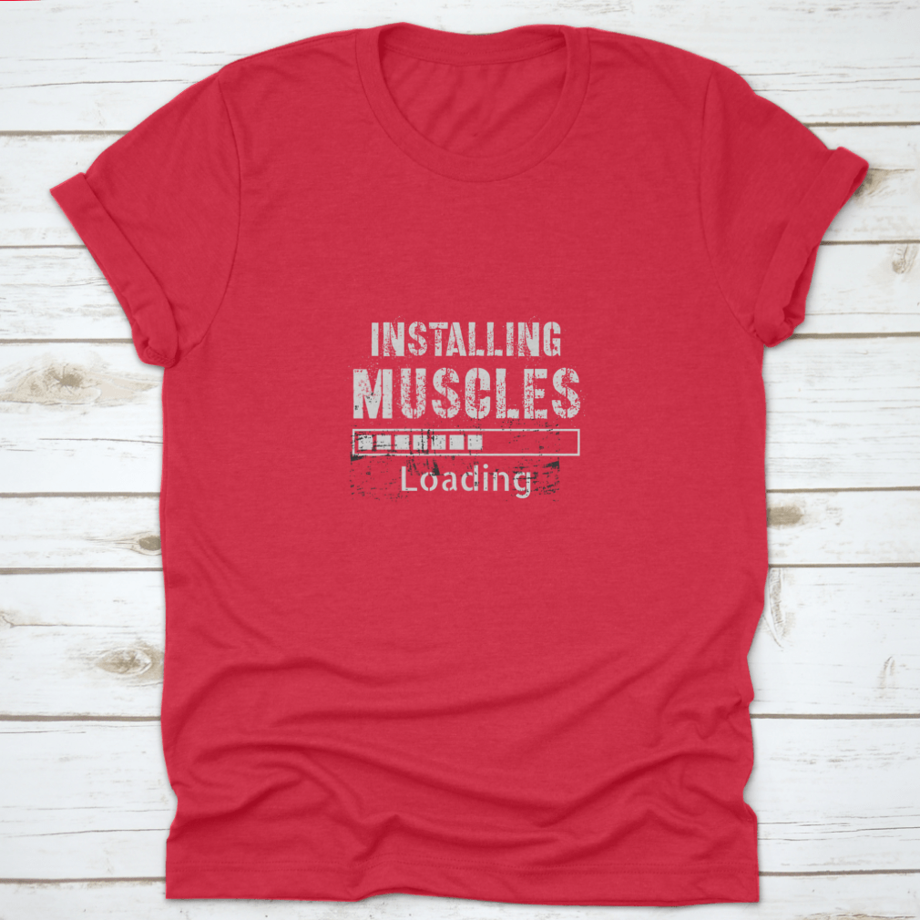 A vintage-inspired t-shirt featuring a grunge background with the phrase 'Installing Muscles', made from 100% cotton for comfort.