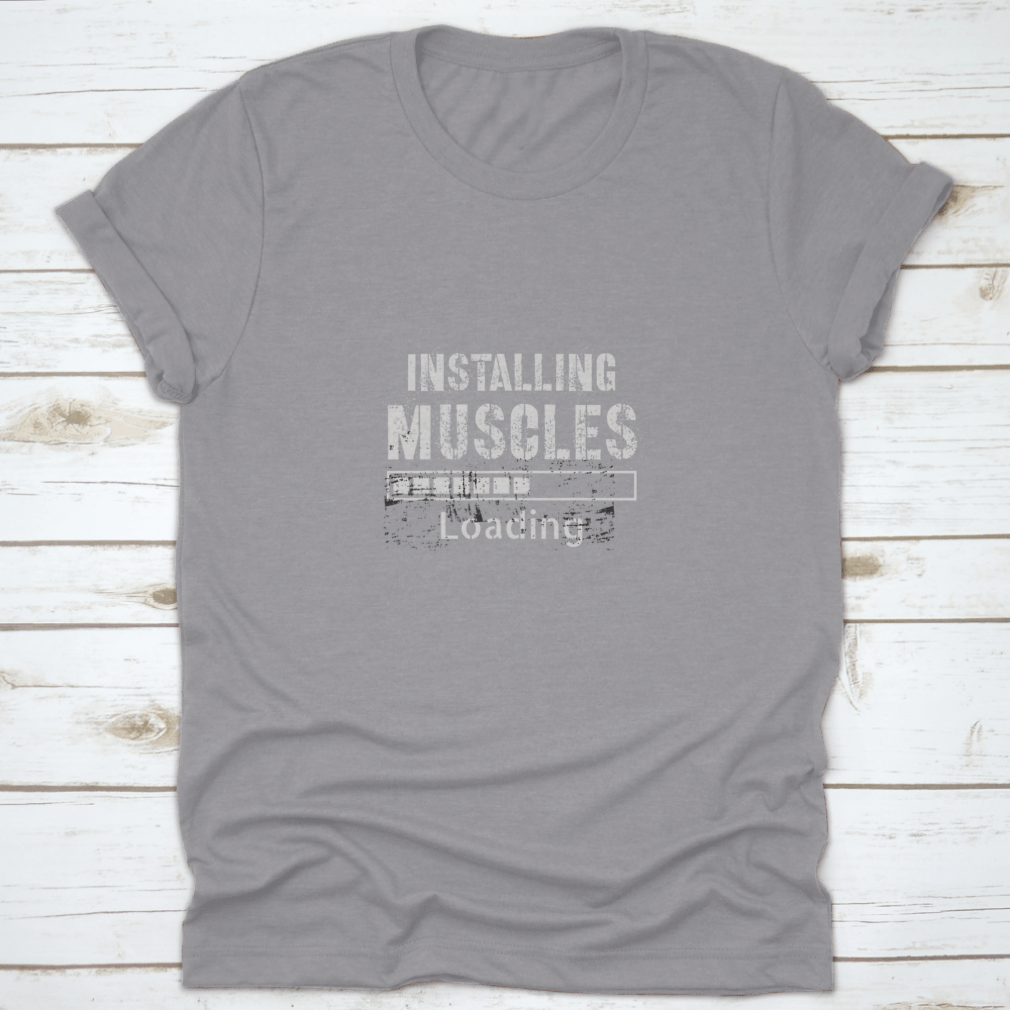 A vintage-inspired t-shirt featuring a grunge background with the phrase 'Installing Muscles', made from 100% cotton for comfort.