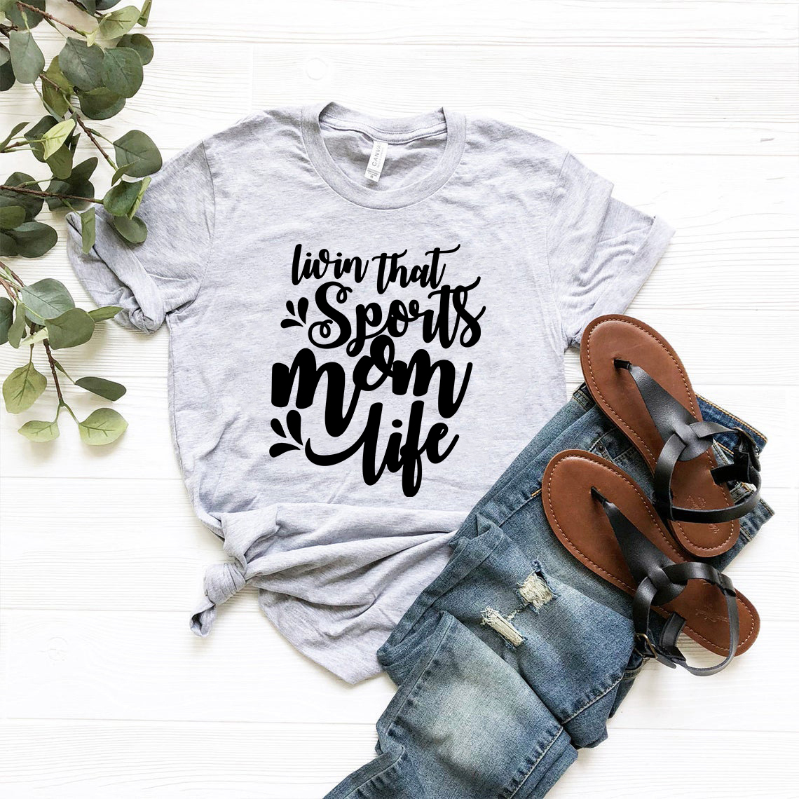 A stylish unisex T-shirt in various colors, featuring the phrase 'Livin That Sports Mom Life' designed for comfort and casual wear.