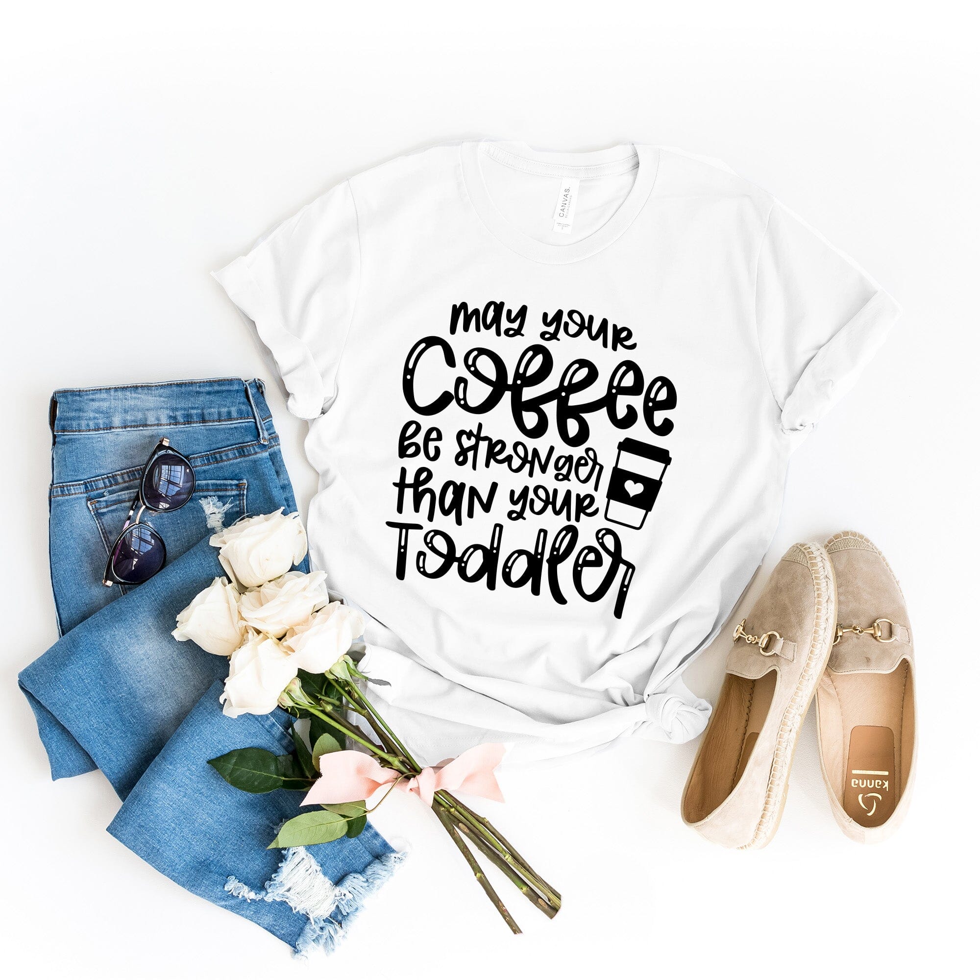 A humorous T-shirt featuring the phrase 'May Your Coffee Be Stronger Than Your Toddler', made from soft cotton, suitable for both men and women.