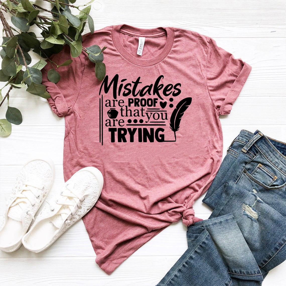 A unisex T-shirt featuring the phrase 'Mistakes Are Proof That You Are Trying' printed on a soft ring spun cotton fabric, available in various colors.