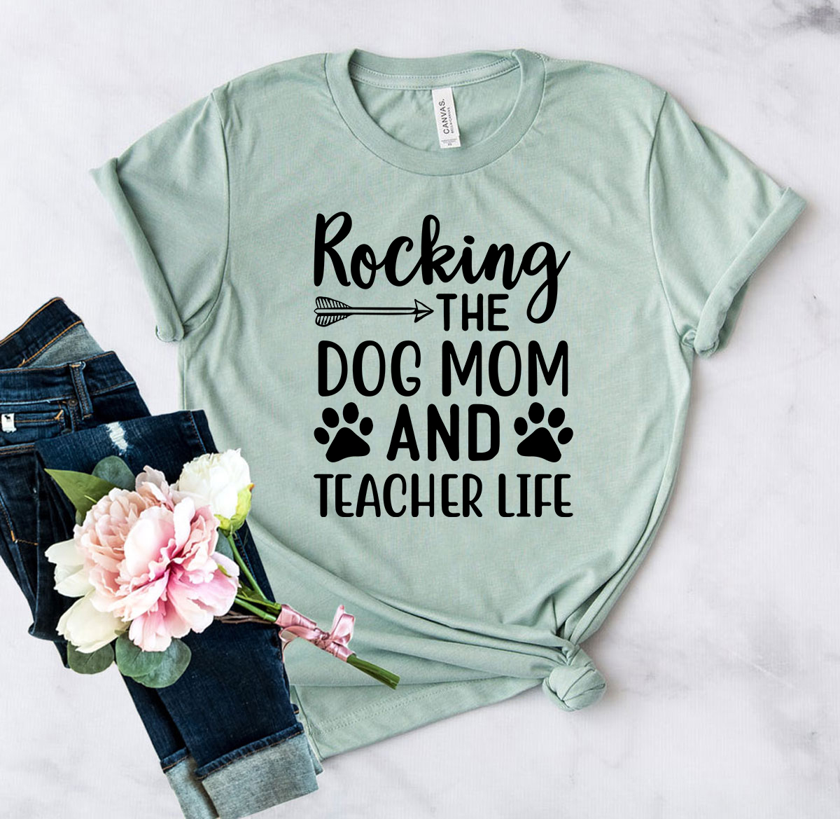 A stylish unisex T-shirt featuring the phrase 'Rocking The Dog Mom And Teacher Life' in vibrant print, available in multiple colors.