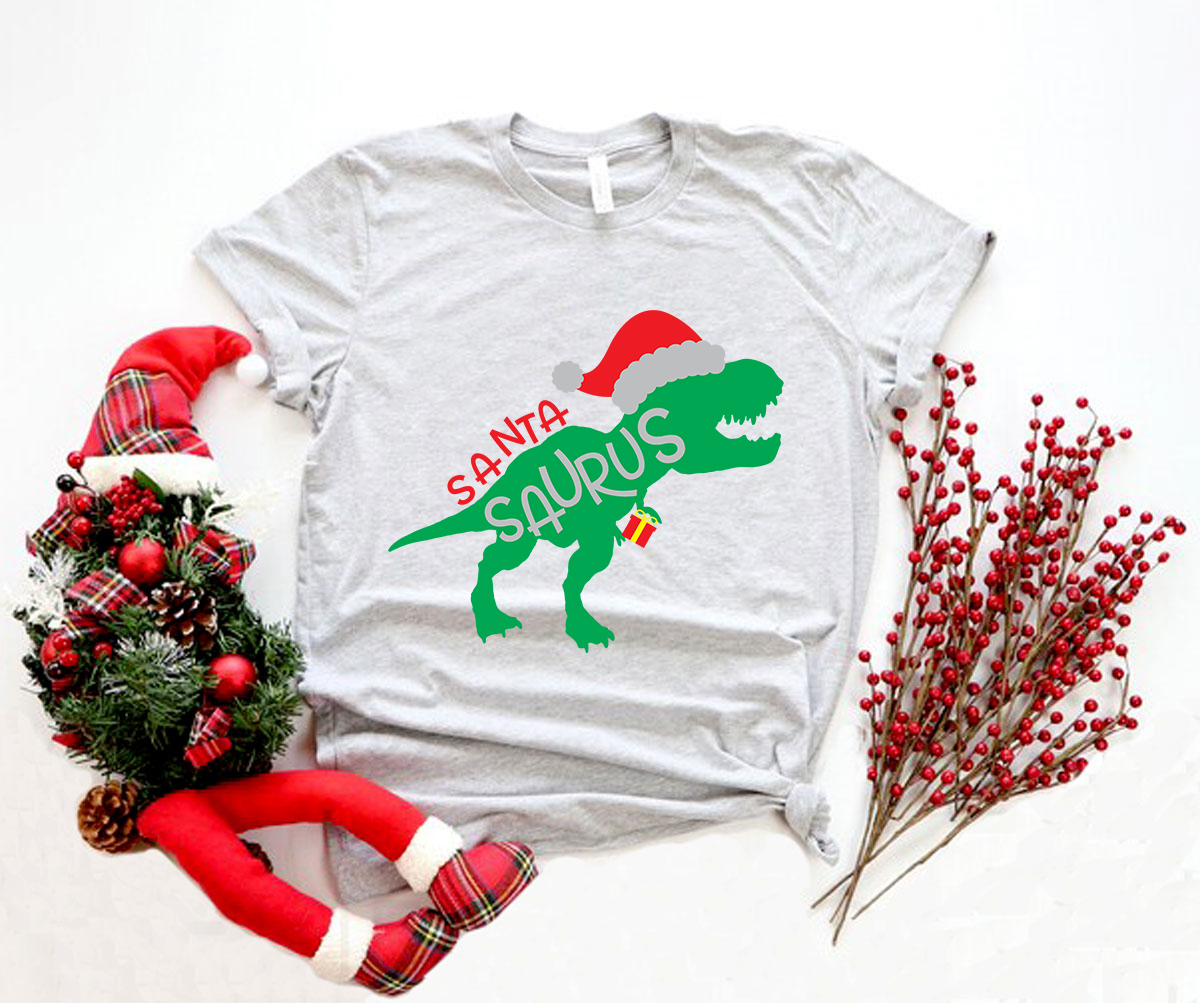 A festive Santa Saurus Shirt featuring a playful dinosaur design, made from soft ring spun cotton, available in multiple colors.