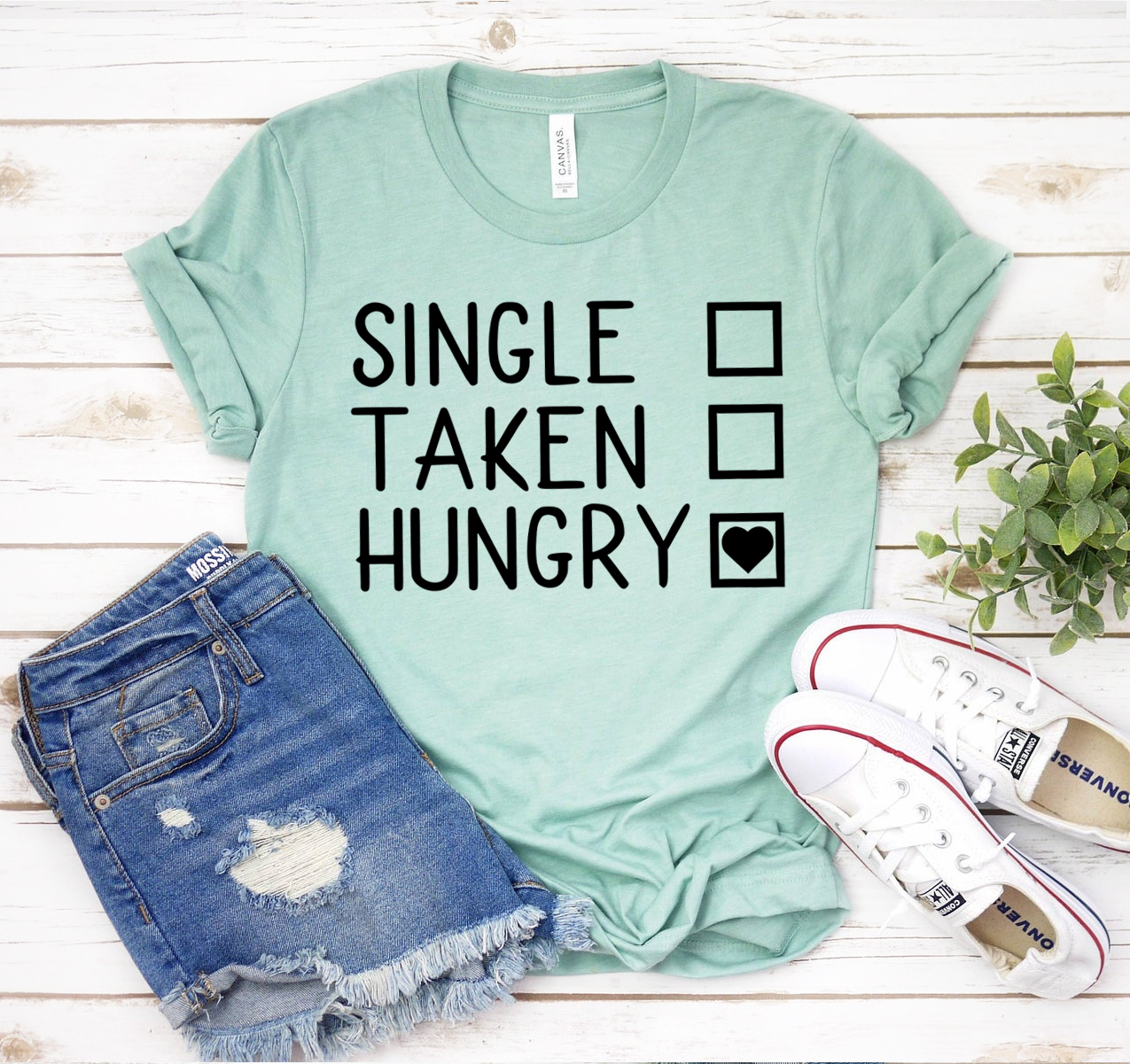 A unisex Single Taken Hungry T-shirt displayed on a hanger, showcasing its soft fabric and humorous design.