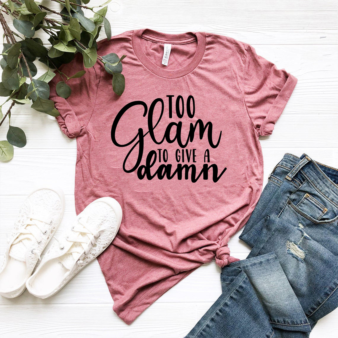 A stylish unisex T-shirt featuring the slogan 'Too Glam To Give A Damn', made from soft ring spun cotton, available in multiple colors.