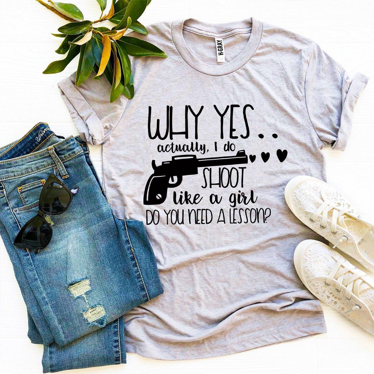 A stylish black t-shirt featuring the phrase 'Why Yes Actually I Do Shoot Like a Girl' in bold print, made from premium quality cotton.