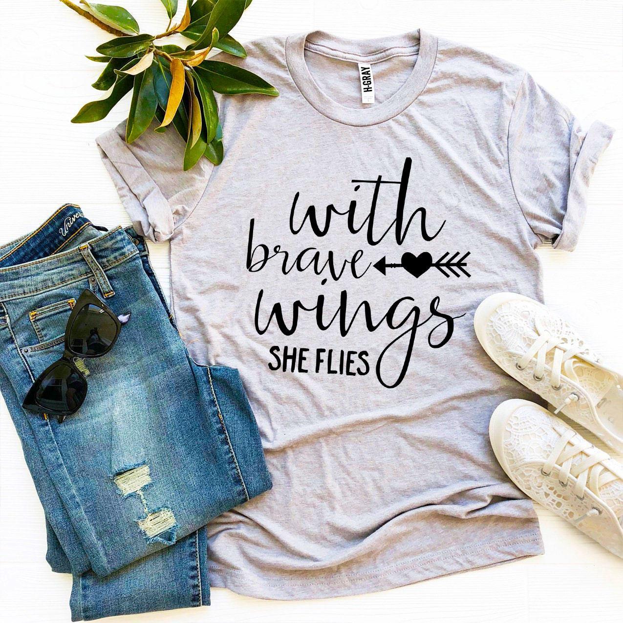 A stylish 'With Brave Wings She Flies' T-shirt made from premium ring spun cotton, featuring a vibrant flex print design.