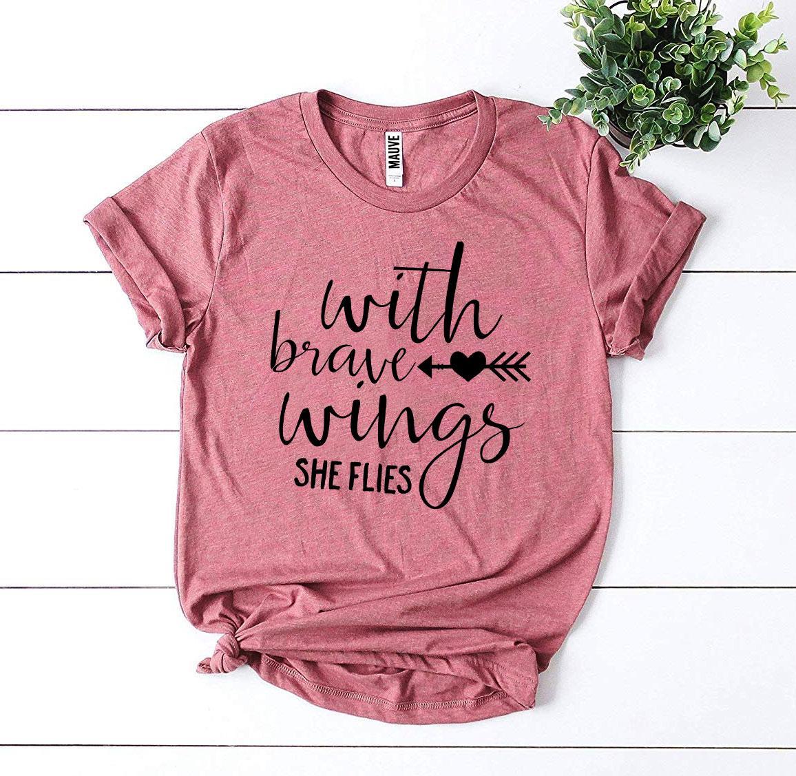 A stylish 'With Brave Wings She Flies' T-shirt made from premium ring spun cotton, featuring a vibrant flex print design.