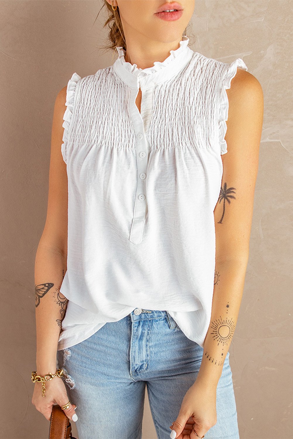 A stylish white mock neck tank top featuring elegant frills, smocked shoulder details, and a button closure, perfect for summer wear.