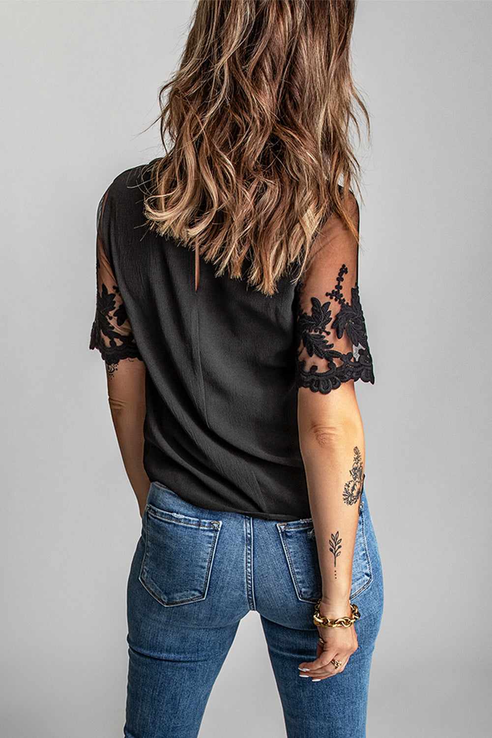 A stylish black lace short sleeve top featuring sheer floral mesh sleeves and a round neckline, perfect for summer wear.