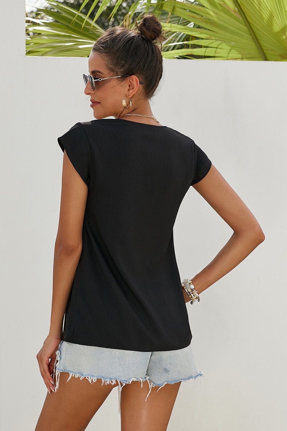 Black short sleeve blouse featuring a bohemian floral print and deep v-neck design, perfect for summer wear.