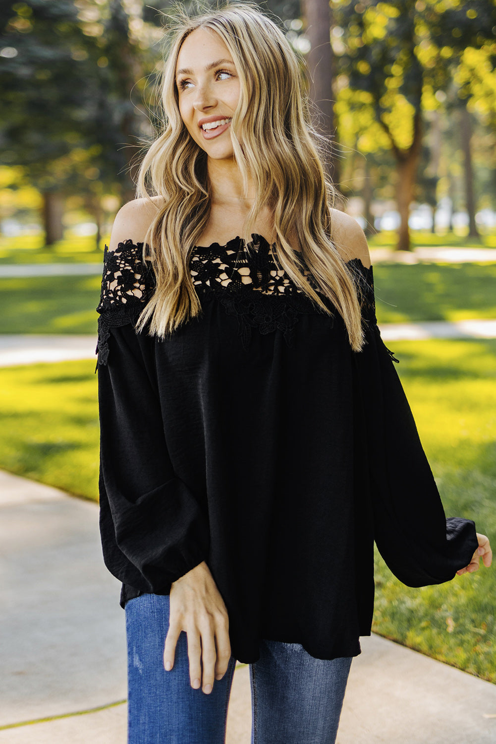 A stylish woman wearing a Blooming Lace Off The Shoulder Top, showcasing its elegant design and lace detailing.