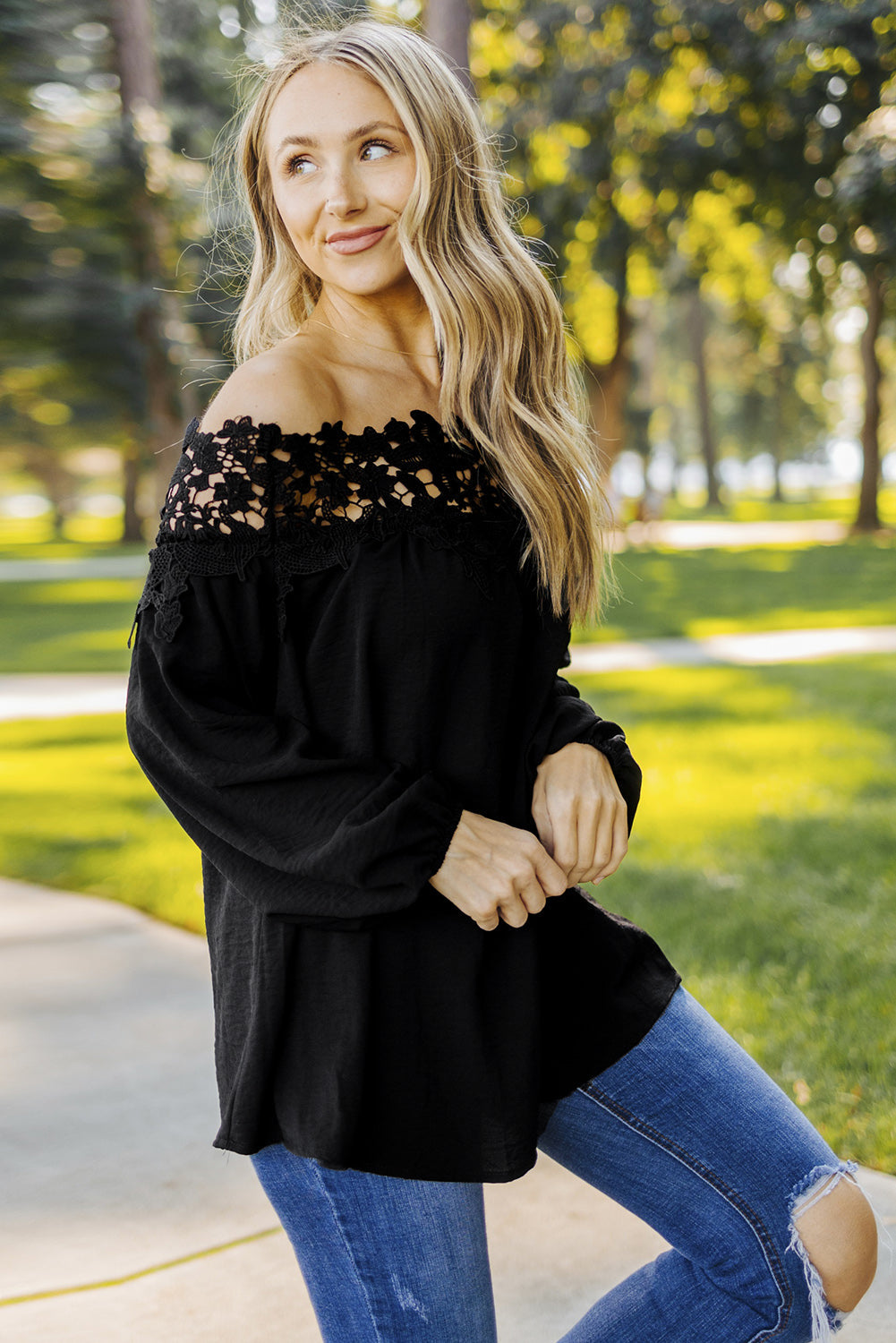 A stylish woman wearing a Blooming Lace Off The Shoulder Top, showcasing its elegant design and lace detailing.