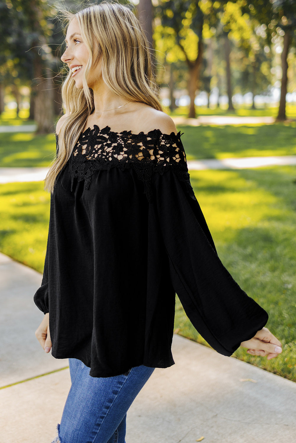 A stylish woman wearing a Blooming Lace Off The Shoulder Top, showcasing its elegant design and lace detailing.