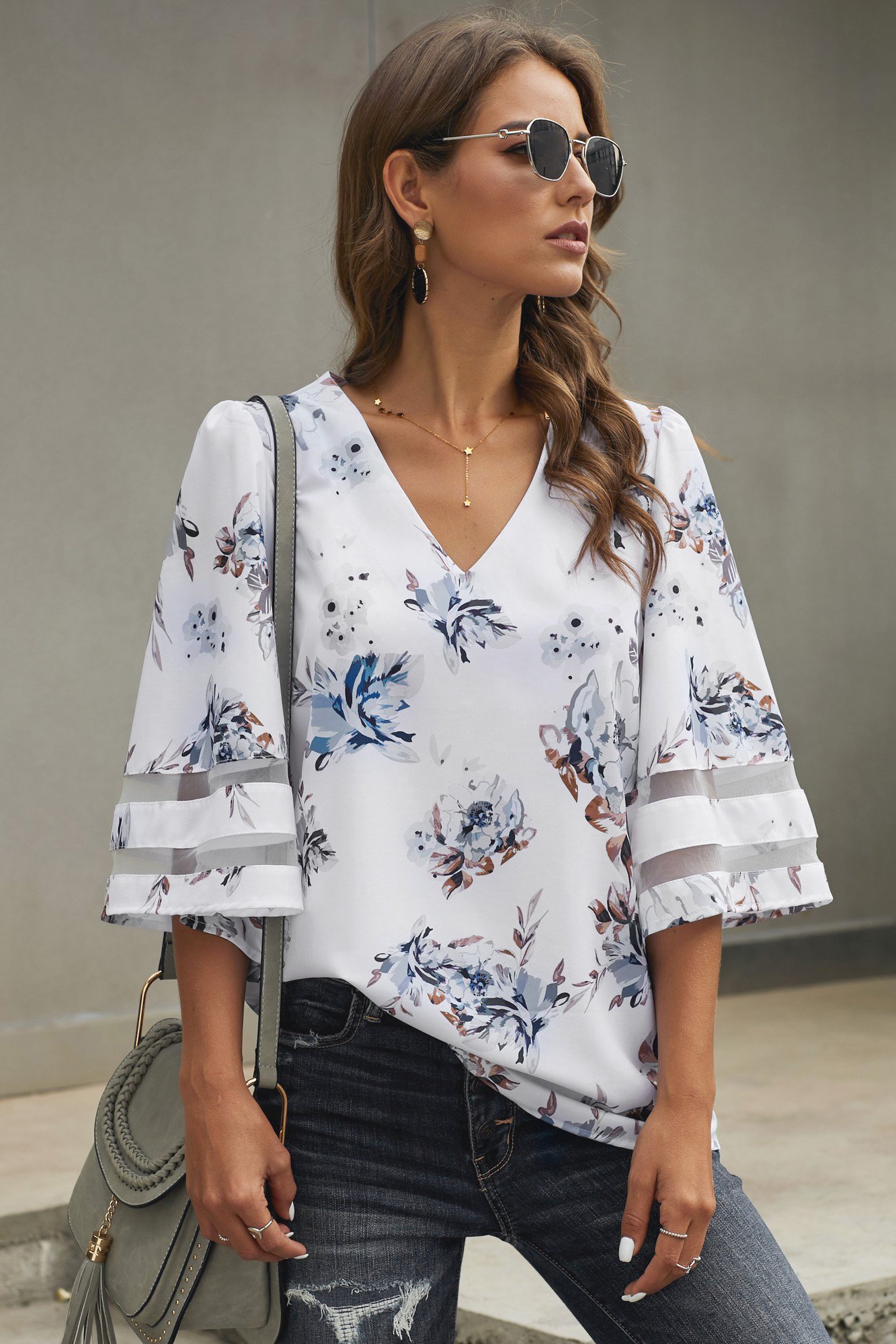 Chic white floral blouse with 3/4 flared sleeves and v-neck design, perfect for casual summer wear.