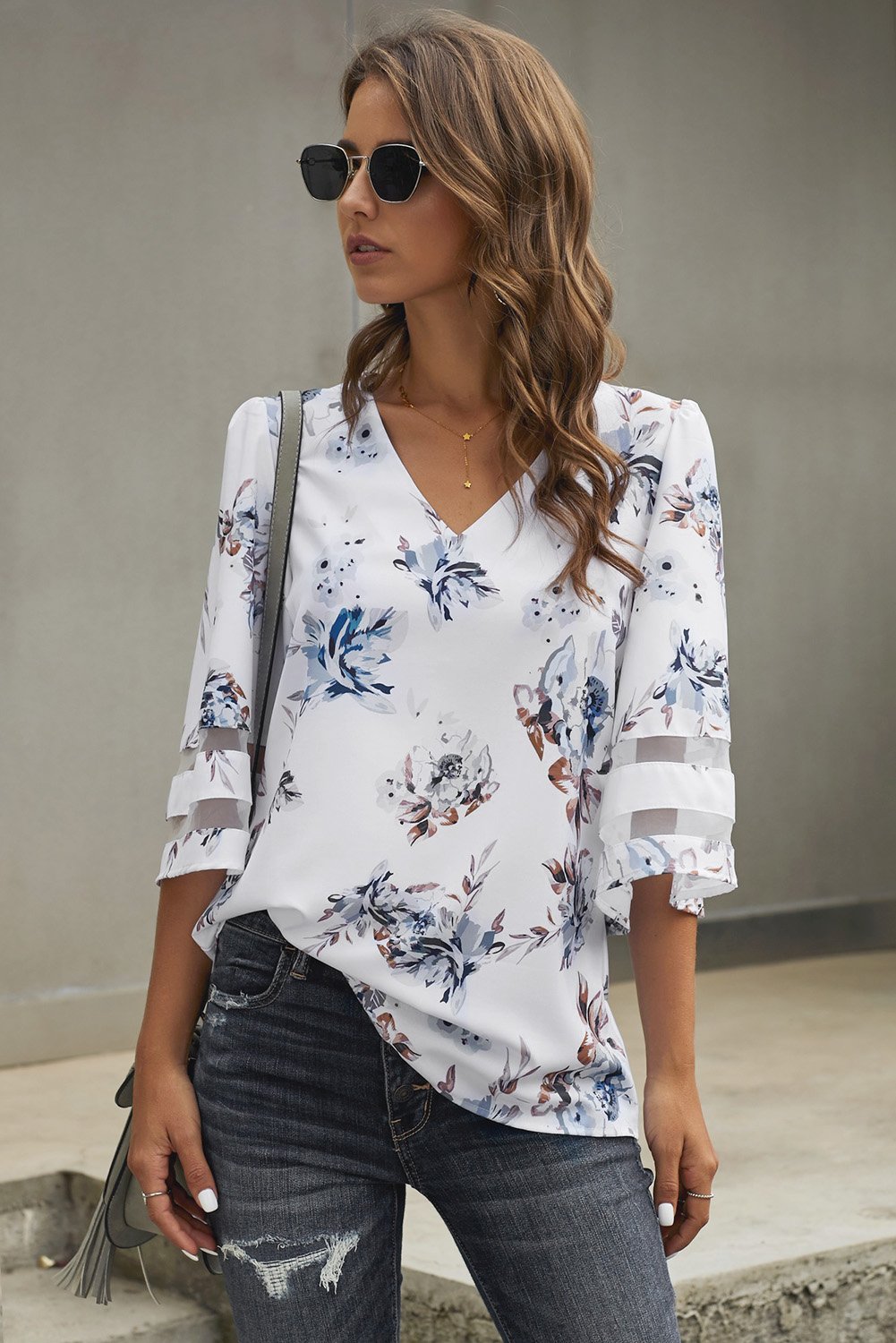 Chic white floral blouse with 3/4 flared sleeves and v-neck design, perfect for casual summer wear.