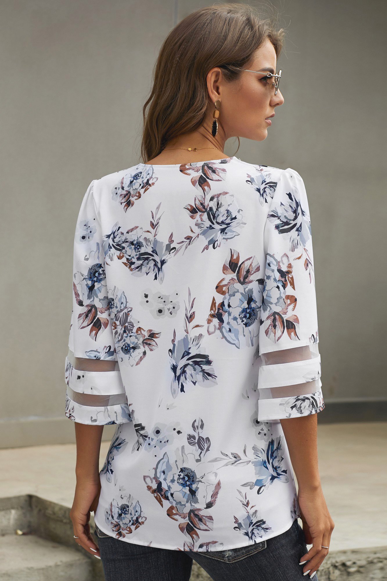 Chic white floral blouse with 3/4 flared sleeves and v-neck design, perfect for casual summer wear.