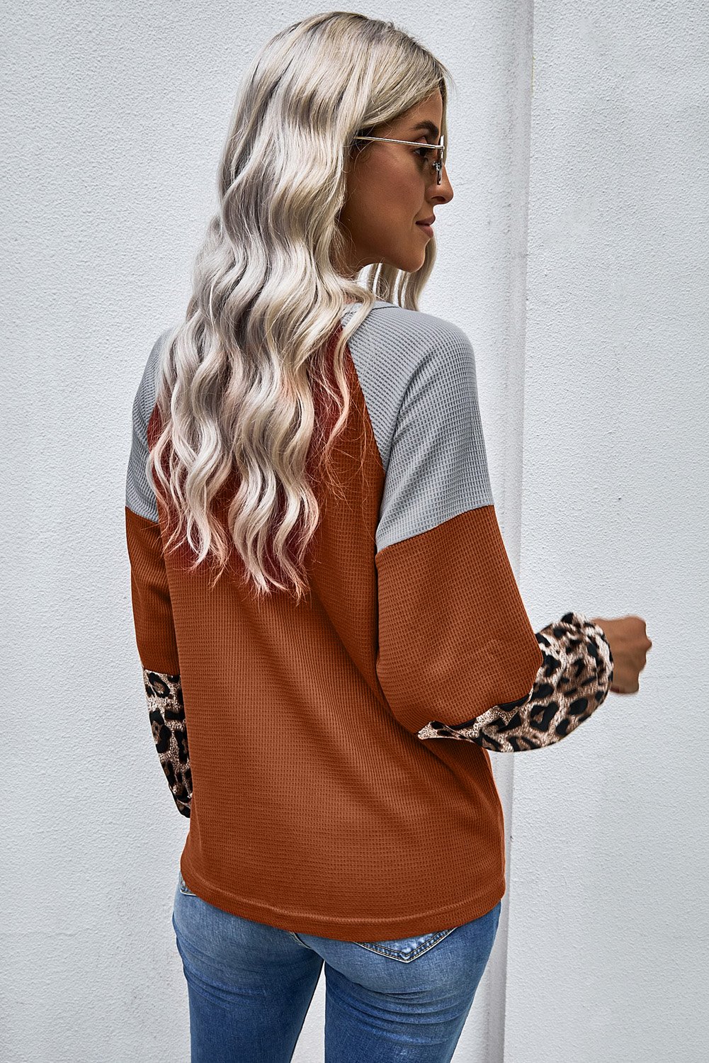 Knit Orange Blouse with leopard print cuffs and relaxed fit, showcasing a stylish design.