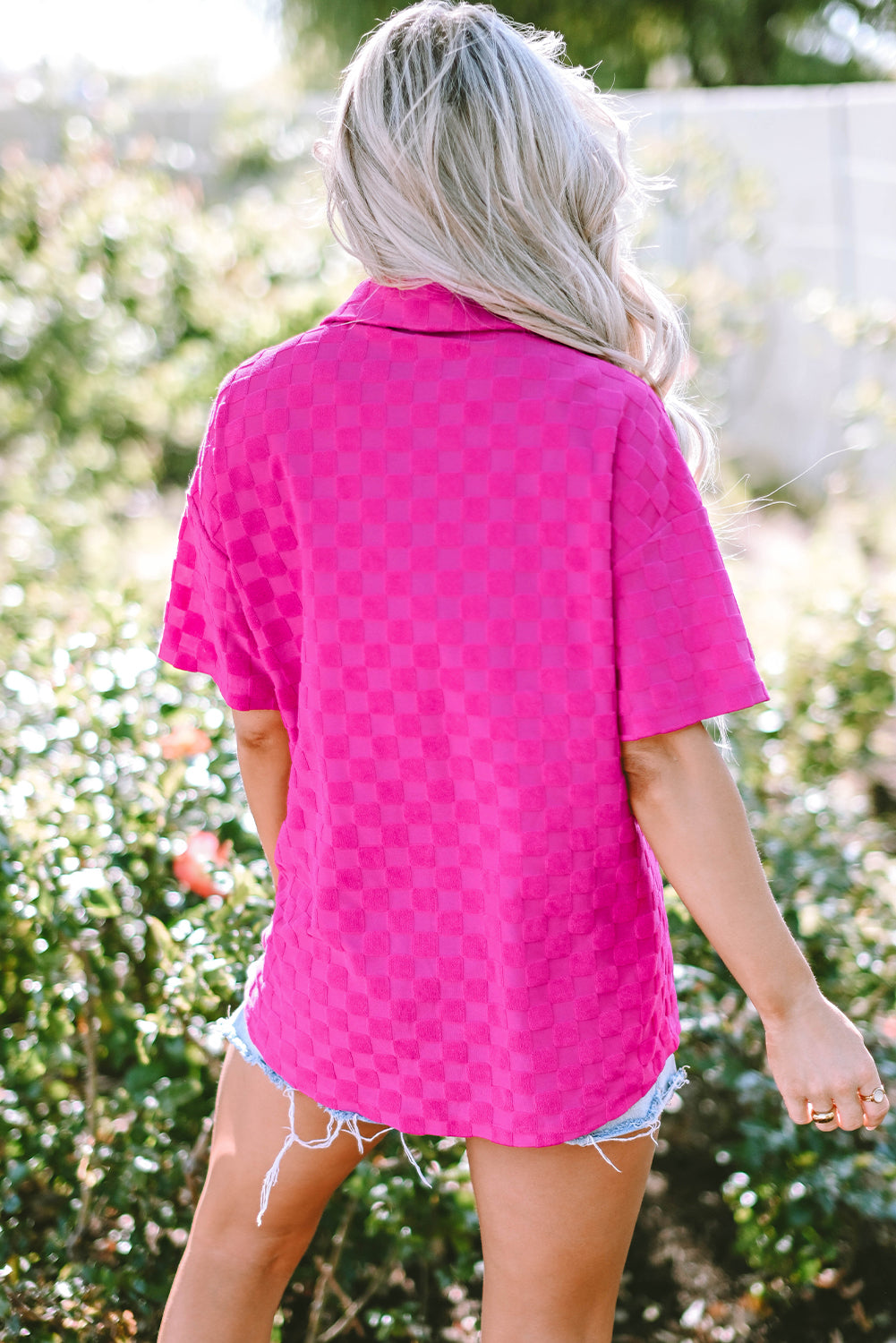 Bright pink lapel textured short sleeve shirt displayed on a hanger, showcasing its elegant design and chic style.