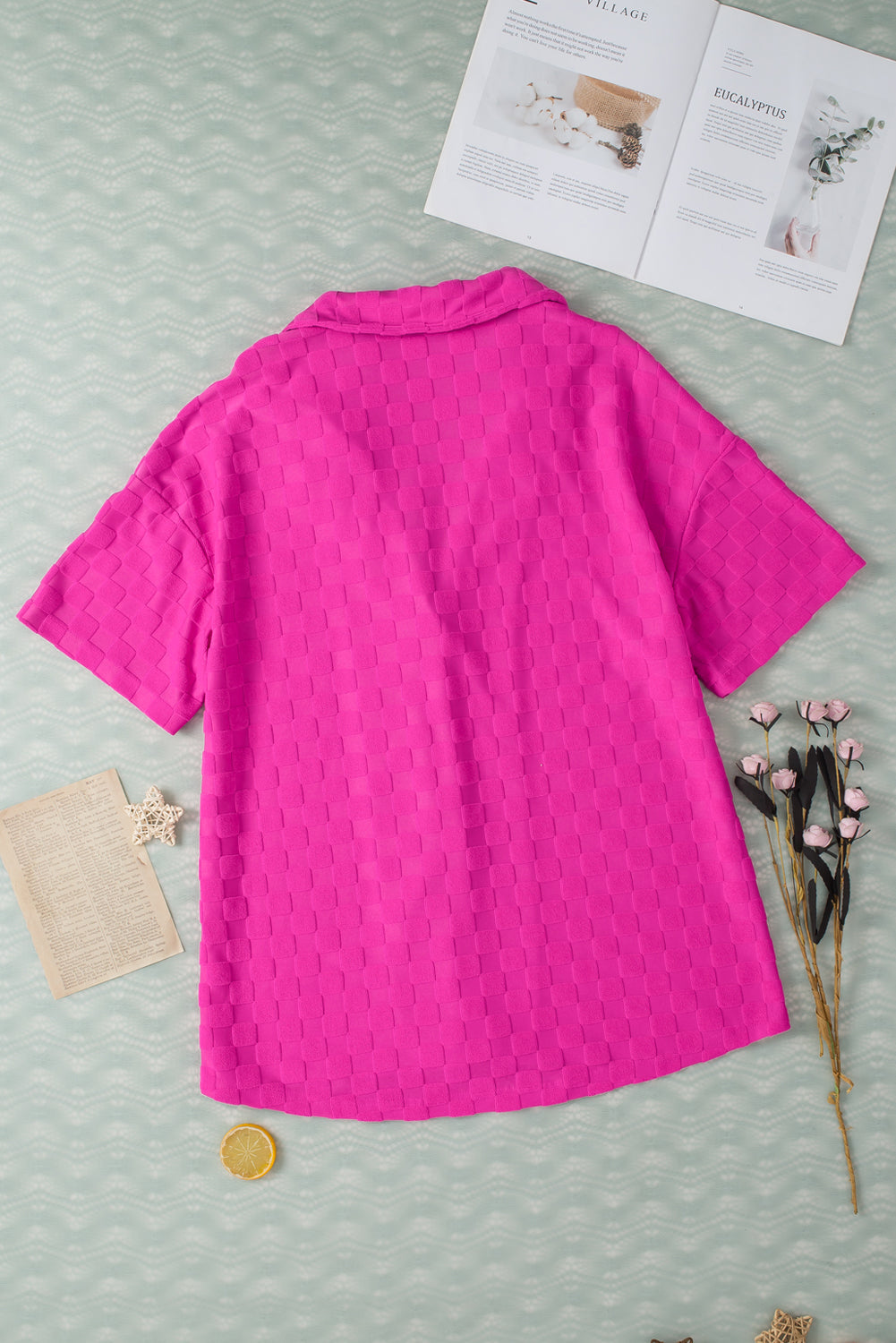 Bright pink lapel textured short sleeve shirt displayed on a hanger, showcasing its elegant design and chic style.