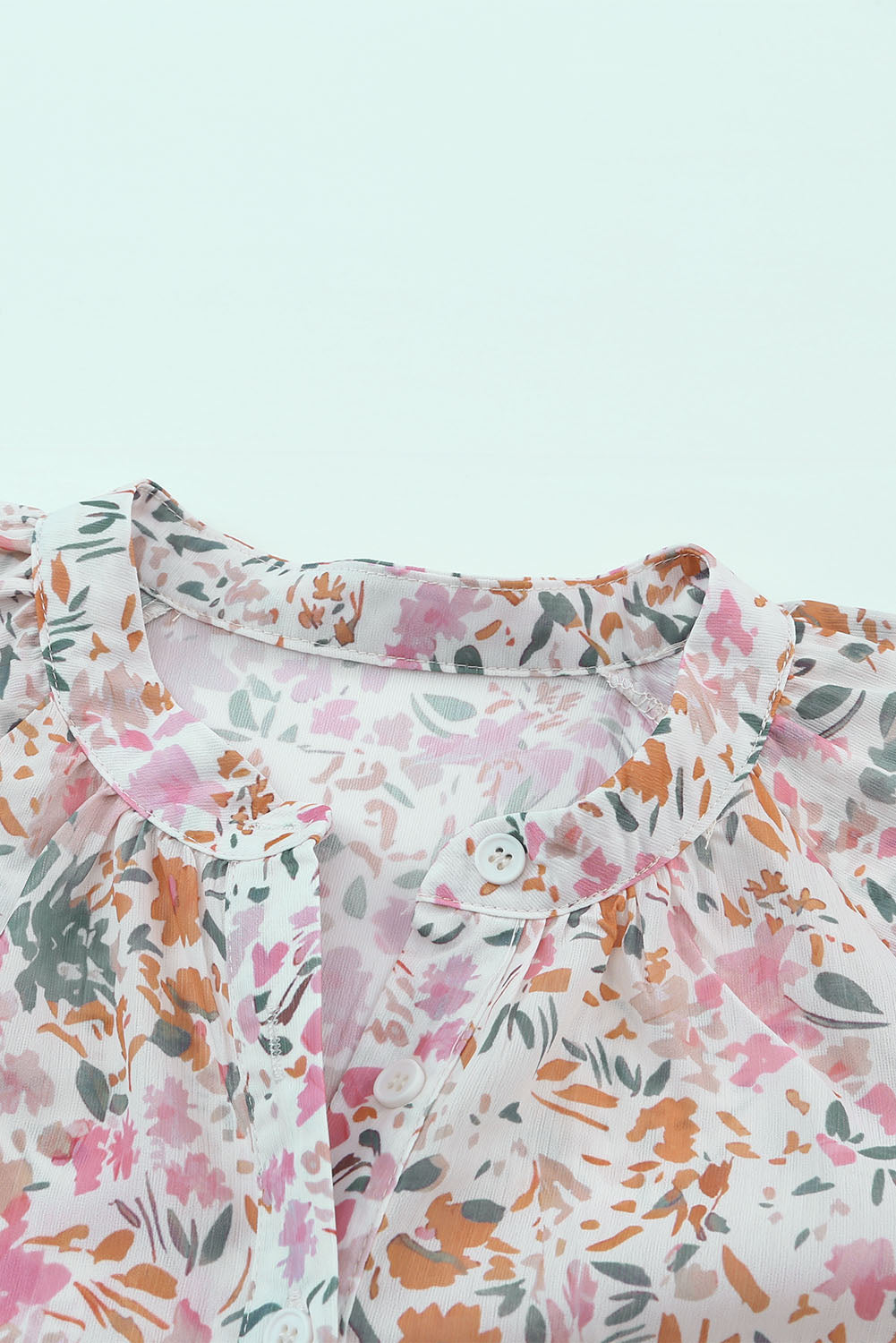 A vibrant multicolor floral mandarin collar top featuring short ruffle sleeves and a half button-front detail, perfect for spring fashion.