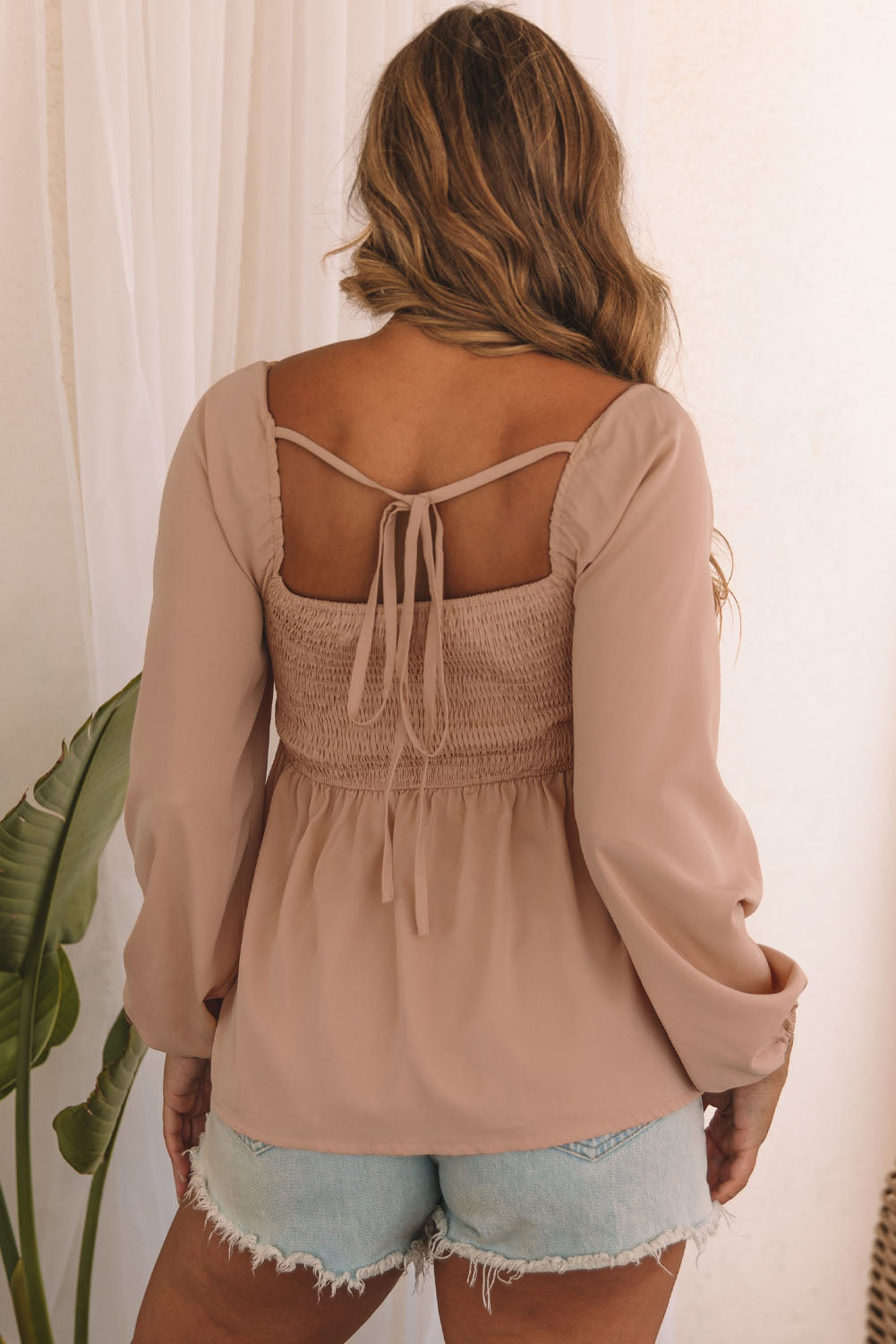 A stylish orange Notched V-Neck Smocked Back Peplum Blouse displayed on a mannequin, showcasing its elegant design and fitted silhouette.