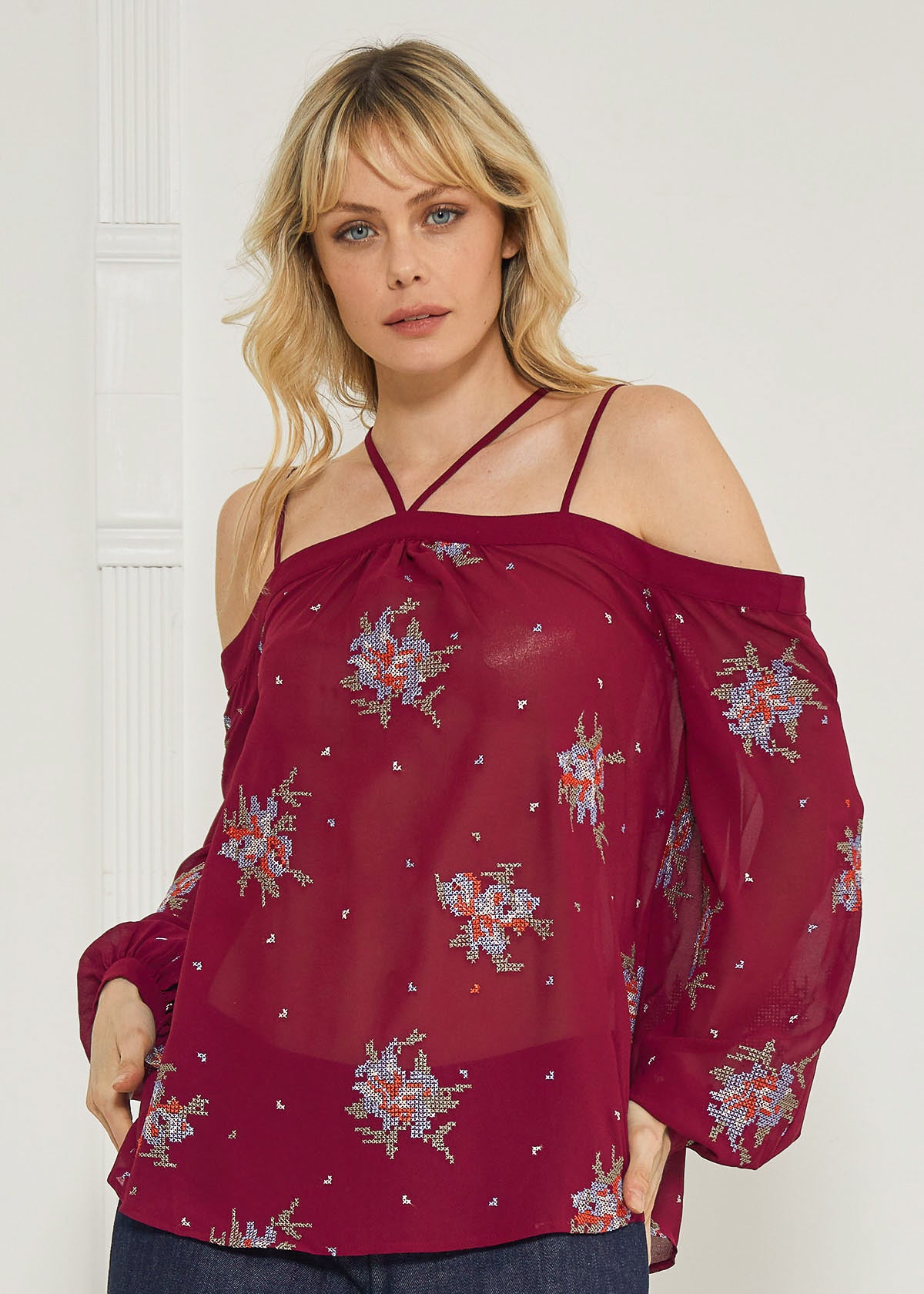 A stylish off-shoulder blouse in burgundy featuring intricate embroidery prints, perfect for dressing up denim outfits.