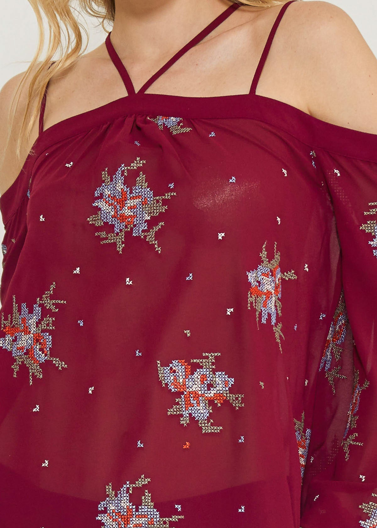 A stylish off-shoulder blouse in burgundy featuring intricate embroidery prints, perfect for dressing up denim outfits.