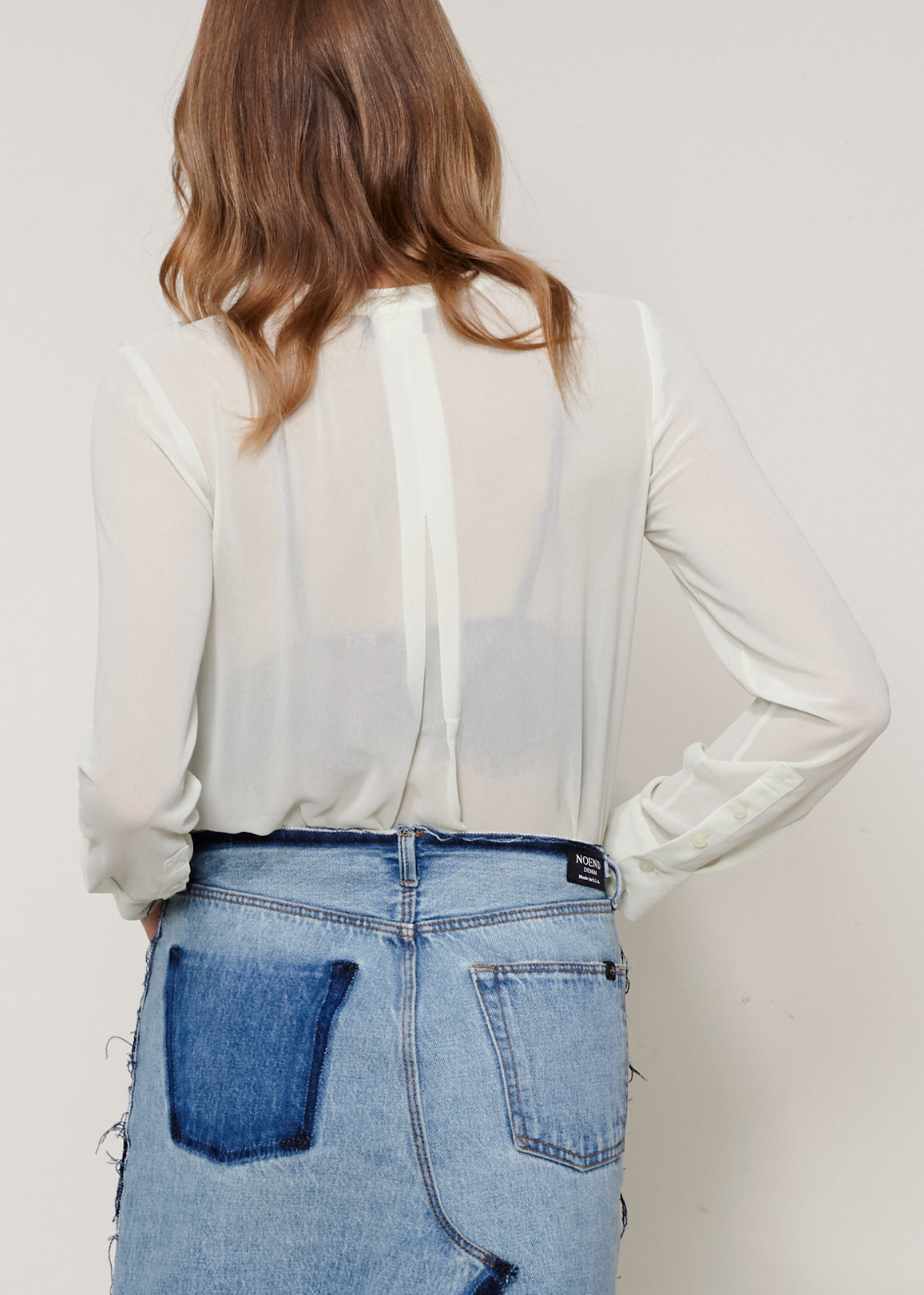 A stylish sheer button-up blouse with long sleeves, round neck, and two pockets, made from 100% polyester.