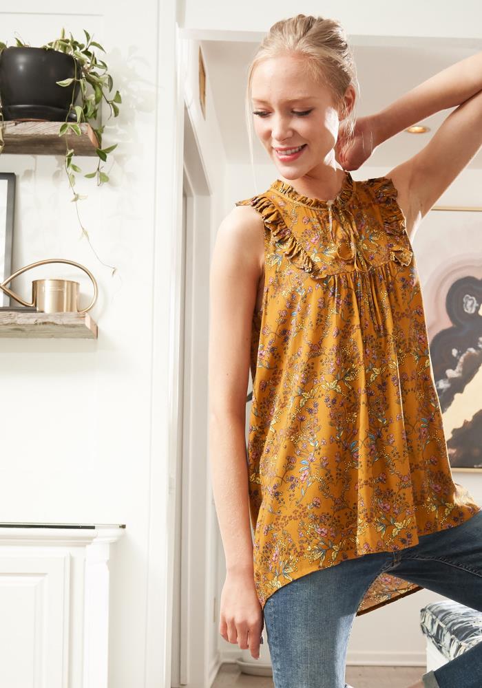 A vibrant sleeveless tie neck blouse featuring a colorful floral print, perfect for warm weather styling.