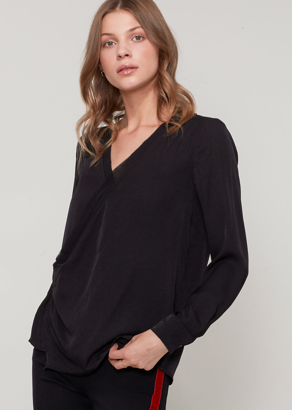 A stylish black V-neck surplice blouse with a zipper front closure, showcasing a sleeveless and cropped design.