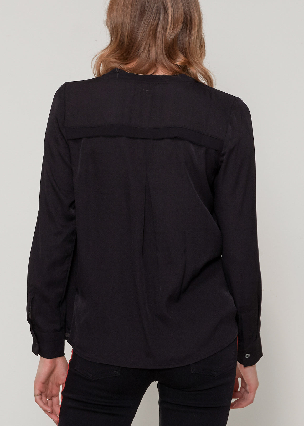 A stylish black V-neck surplice blouse with a zipper front closure, showcasing a sleeveless and cropped design.