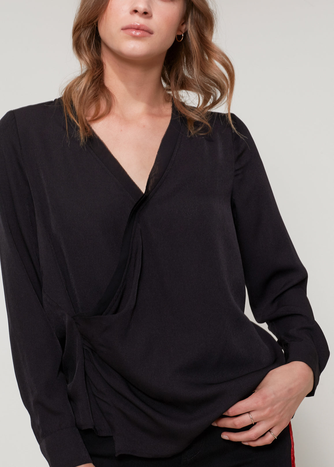 A stylish black V-neck surplice blouse with a zipper front closure, showcasing a sleeveless and cropped design.