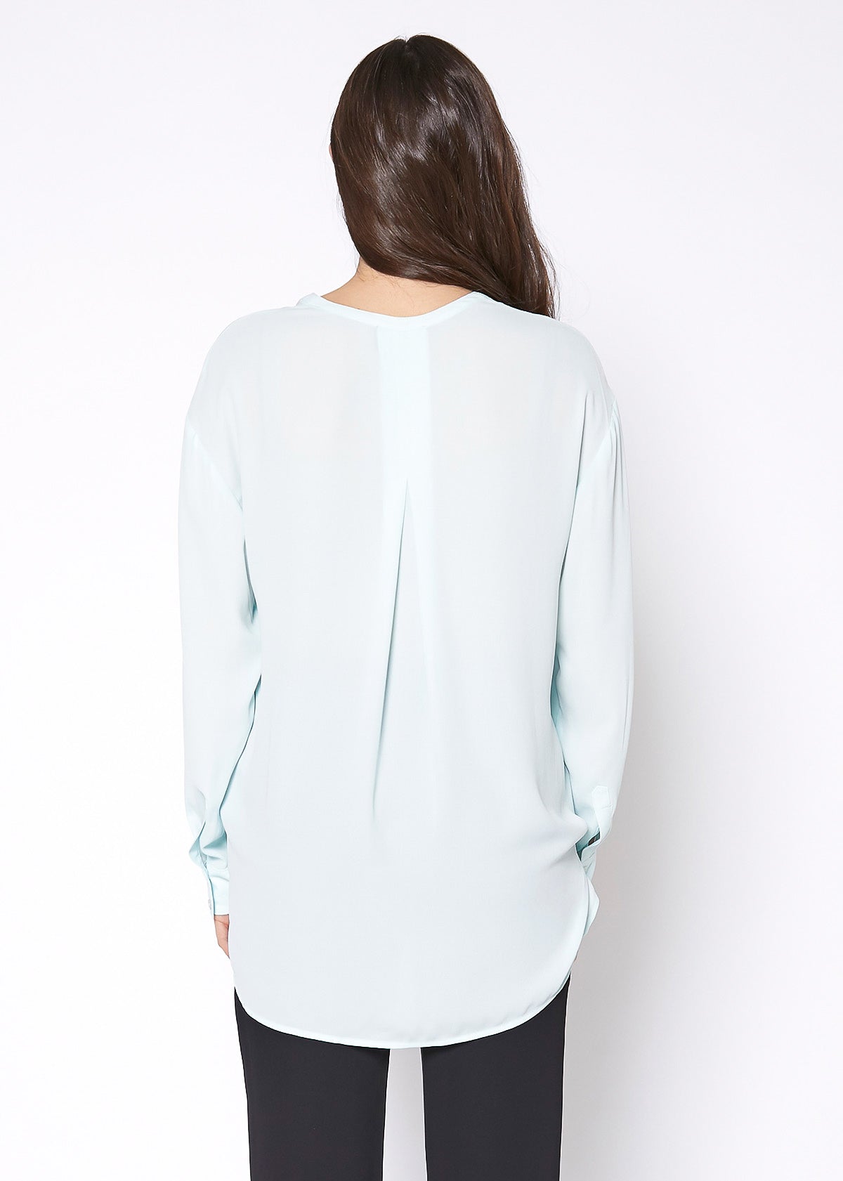 A stylish V-Neck Wrap Hem Blouse featuring a pleated front and hi-lo design, with long sleeves and single button cuffs, made from 100% polyester.