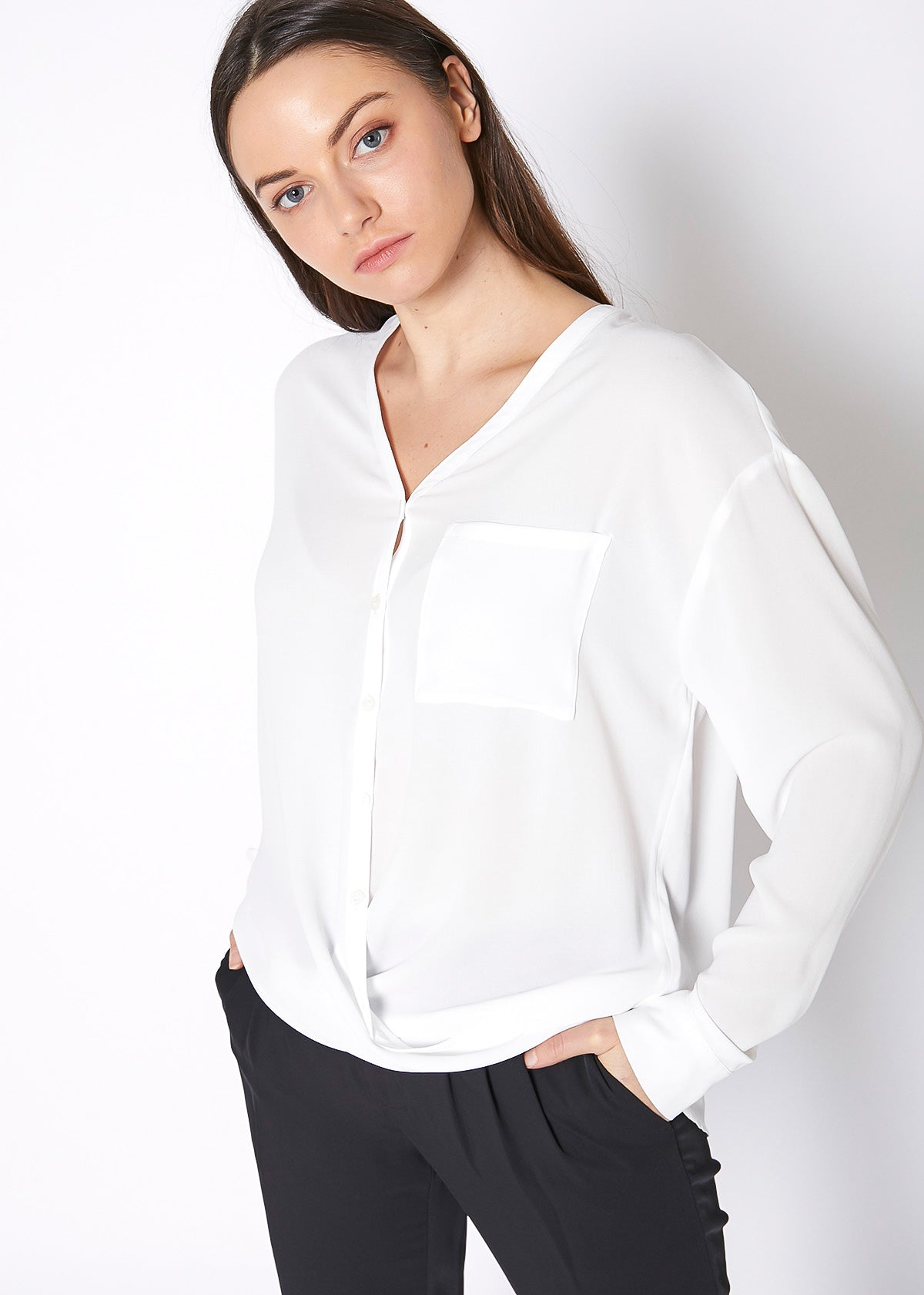 A stylish V-Neck Wrap Hem Blouse featuring a pleated front and hi-lo design, with long sleeves and single button cuffs, made from 100% polyester.